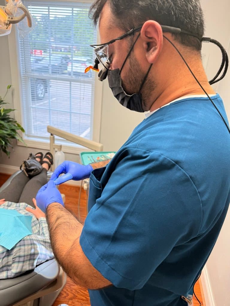 A Roanoke Dental Center hygienist in blue scrubs working chairside with a patient