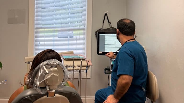 A Roanoke Dental Center clinician walking a patient through images on a chairside display