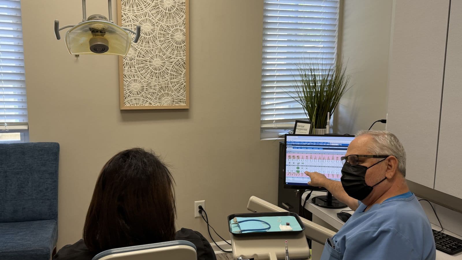 A Roanoke Dental Center clinician reviewing dental X-rays on a chairside monitor with a patient